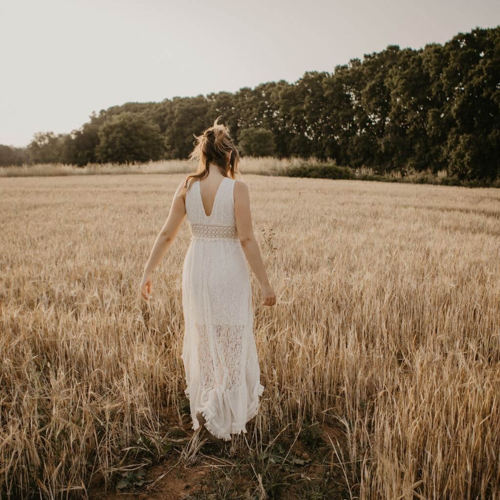 Myriam Peña caminando en un campo dorado, símbolo de introspección, introduciendo el módulo de Sanación Emocional Taoísta en la Certificación en Sexualidad Femenina Taoísta – La Mujer Oceánica | Escuela de Mujeres