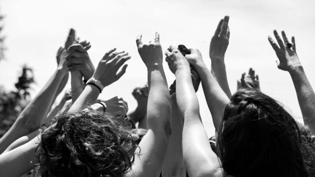 Manos de mujeres alzadas al cielo en un gesto ceremonial, simbolizando el legado y la transmisión de la antorcha sagrada, en la Certificación en Sexualidad Femenina Taoísta – La Mujer Oceánica | Escuela de Mujeres